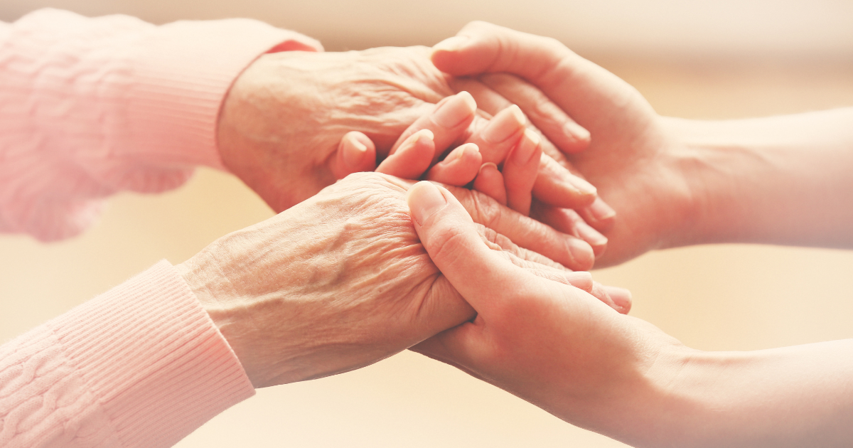 Close-up of a caregiver gently holding an elderly person’s hands, showing emotional support, comfort, and human connection.