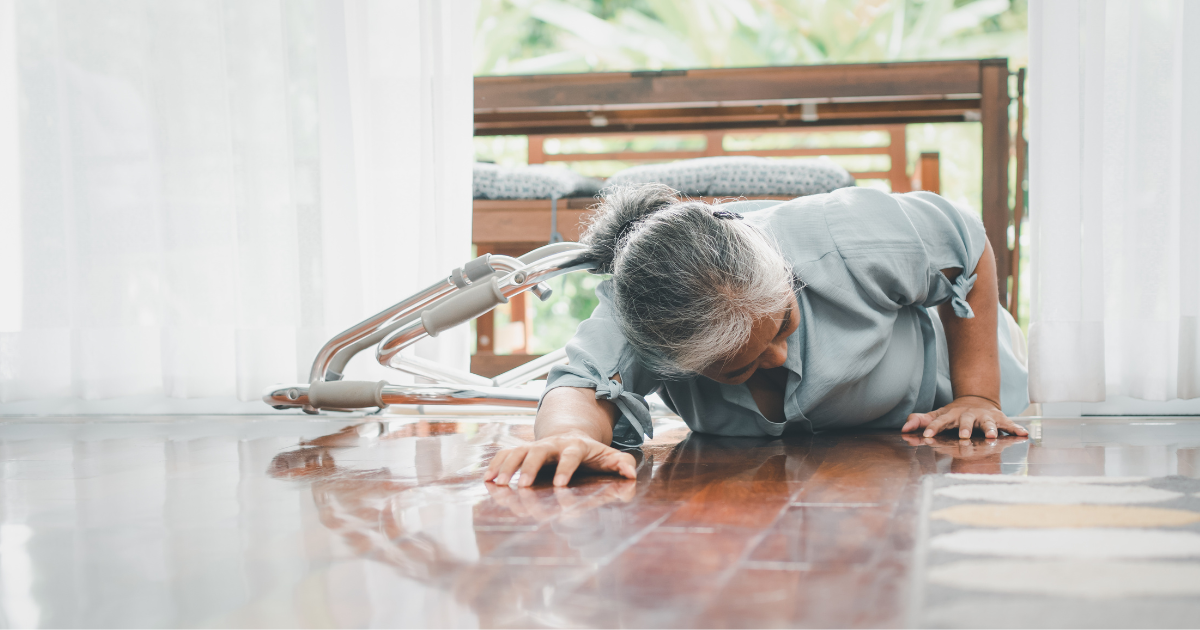 Elderly woman lying on the floor next to a fallen walker after a slip inside her home.