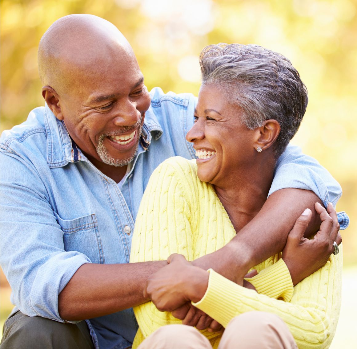 Happy Senior Couple Sharing a Loving Moment Outdoors Smiling elderly couple sitting outdoors and sharing a warm embrace in a peaceful natural setting